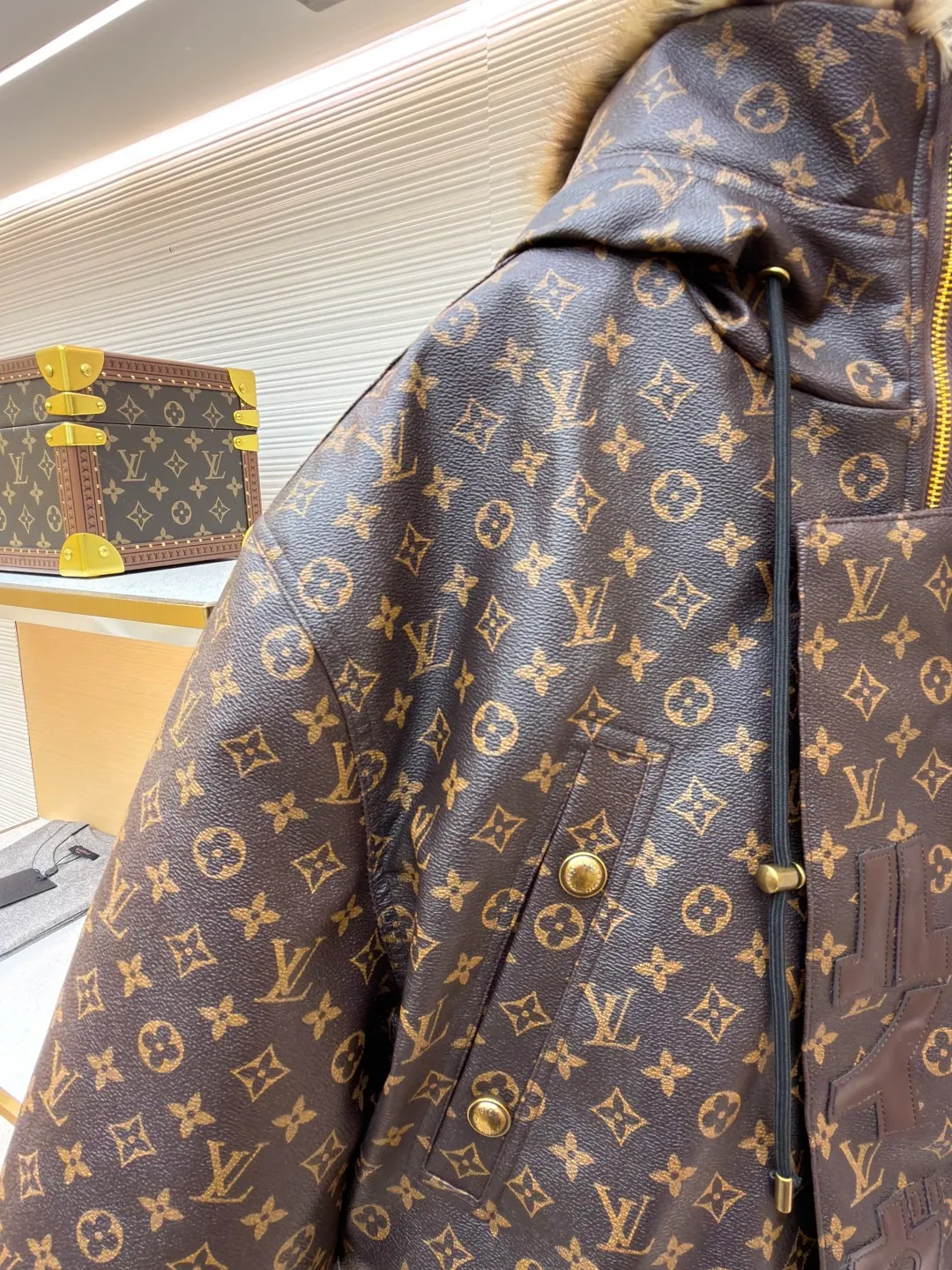 LOUIS VUITTON letter print hooded jacket ●Original version: Purchased and developed for 69999 ●Item number: 1681985-E40 ●Fabric: cotton fabric ●Technology: printing production ●Color: brown ●Version: fitted version ●Weight: about 1810 grams ●Size: 46-48-50-52 ●Description: This printed jacket is made of embossed leather fabric with a dark brown base and is fully printed with the classic Monogram pattern. The embossing process gives the logo a three-dimensional texture. The edge of the hood is spliced ​​with a natural fur collar, and the brim is equipped with an adjustable drawstring (metal rope buckle) to enhance warmth and style. The placket is double-closed with a two-way metal zipper and brass snap buttons. The zipper puller and snap button are both engraved with the brand logo, which is thick and durable. The body is designed with multiple pockets, and the pockets are edged with the same material + metal snap buttons for reinforcement. The left sleeve is equipped with a hidden adjustment tab. The interior is filled with high-fill down cotton, and the stitching adopts diamond-shaped quilting technology to prevent the filling from shifting. The seams are edged with leather of the same color, and the overall wiring is precise, taking into account warmth retention and luxurious texture. The overall wiring is straight and delicate, the fabric is comfortable and soft, and the color is consistent without color difference. It can be matched with the same style to create a fashionable look and control various occasions. Customized accessories, complete with three standards, same style for men and women!